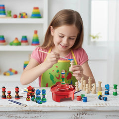 KidzLabs Gamemaker Chess Designer Kit on a wooden table with a young girl in a green and yellow apron, featuring colorful toy