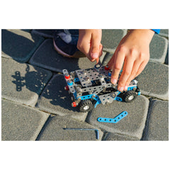 Child assembling a metal and plastic police car from the Alexander Constructor set on a stone pavement.