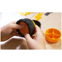 Child assembling Alexander Constructor Jay Ruspa wheel with orange and black parts on a wooden table.