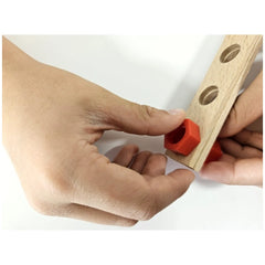 Hands assembling a wooden piece with red plastic connector from the Alexander Maly Constructor Junior set.