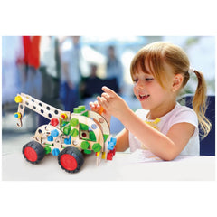 Girl assembling colorful wooden helicopter construction set with bright parts, smiling in sunlight.