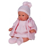 Koke, a 36 cm Asi Doll, in a soft pink duffle coat, dress, and hat with pom-poms, seated with lifelike blue eyes.