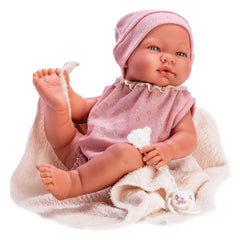 María doll in pink knitted bodysuit and hat, holding a white teddy pacifier, sitting on a beige blanket.