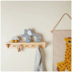 Wooden pull-along elephants in gray and yellow, resting on a wooden shelf with hooks, against a pale wall. A textured wall hanging features a cartoon giraffe.