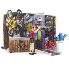 Toy bike shop playset with figure organizing helmets, featuring colorful walls and mounted bicycles.