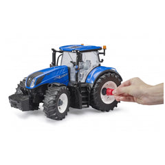 Blue Bruder New Holland T7 315 toy tractor with detailed design, large black tires, clear cab, and a hand adjusting the wheel.