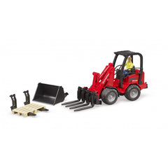 Red Bruder Schäffer Compact Loader with a figure, pallet forks, bucket, and accessories on a white background.