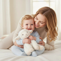 Artesavi White Lamb Plush 18 cm, held by a smiling woman in a serene room, with a baby in a blue onesie beside her.