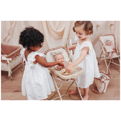 ASI Dolls high chair with tray and bib, in a warm, inviting scene with children feeding a baby doll. Soft pastel colors enhan