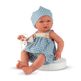 ASI Dolls - Maria Collection Set Noel with Crown features a light-skinned doll in a blue gingham dress and hat, seated on a b
