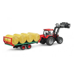 Red tractor toy with a green bale transport trailer carrying eight yellow round bales.