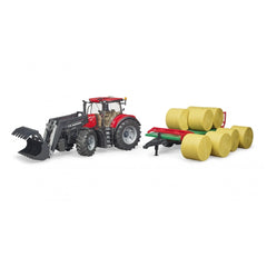 Red Bruder Case IH Optum 300CVX tractor with bale transport trailer carrying yellow hay bales.
