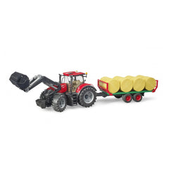 Red Bruder Case IH Optum 300CVX tractor with bale transport trailer carrying yellow round bales on white background.
