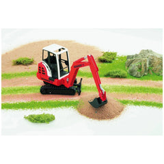 Red Bruder Schaeff HR16 mini excavator with movable arm in a sandbox setting, surrounded by greenery and rocks.