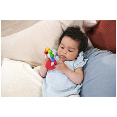 Eichhorn Eh Baby Wooden Teething Ring held by a focused baby on a soft blue blanket, surrounded by colorful spheres.