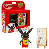 GOLDEN BEAR Lets Paint with Bing toy figure in red and yellow clothing, with green eyes, alongside a whiteboard on a wooden e