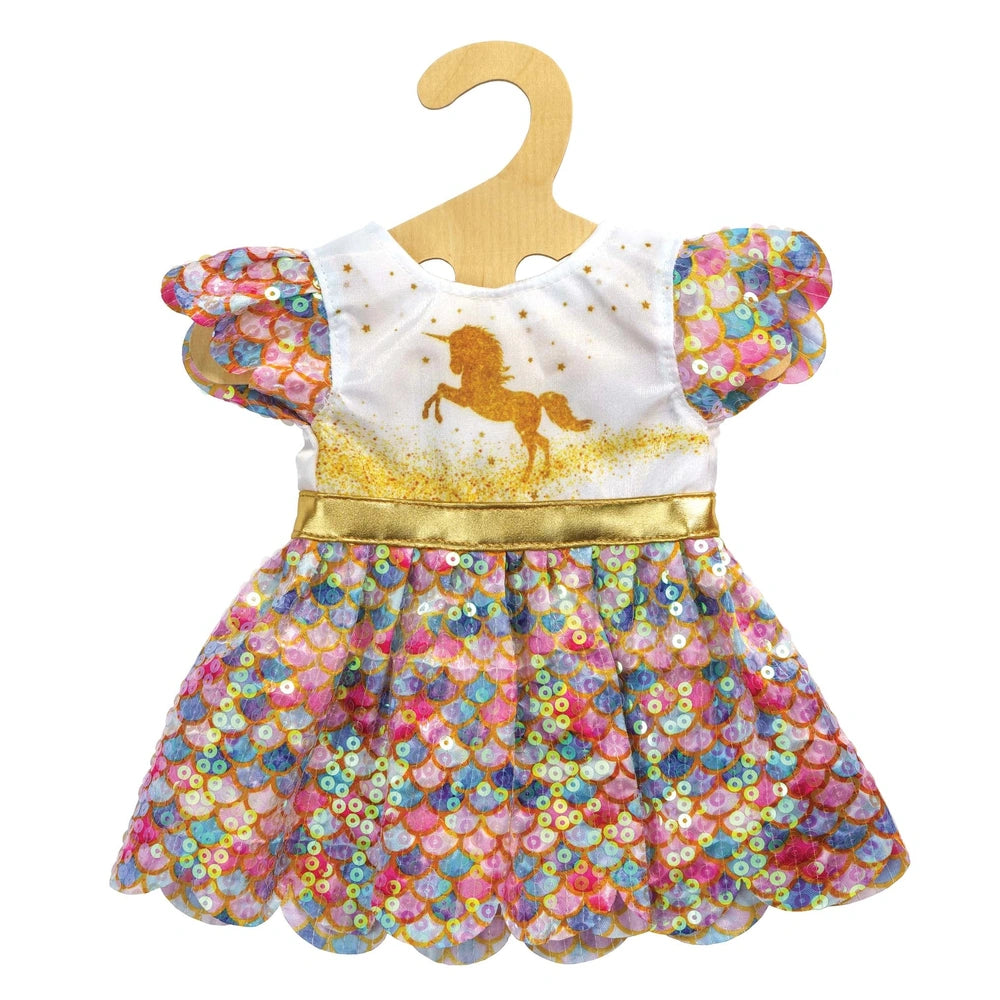 Glitter dress for dolls features a shiny white bodice with unicorn and stars pattern, gold trim, and ruffled hem on a wooden