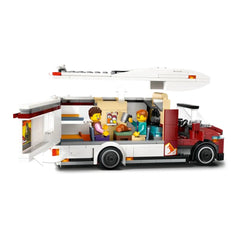 Colorful LEGO® City Holiday Adventure Camper Van set featuring two minifigures inside, equipped with a kitchen, dining area, and sleeping spaces.