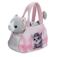 Gray and white plush cat with blue eyes sitting inside a pink bag with a shiny handle on a flat surface.