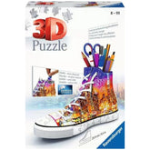Ravensburger 3D puzzle packaging showcases a vibrant sneaker with a cityscape design, featuring bright colors and white laces