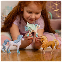 Stormy Unicorn Foal figurines are held by a smiling girl with red hair, sitting on a wooden floor in a purple shirt.