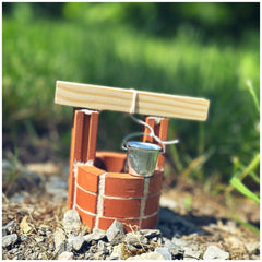 Teifoc well kit featuring brown wooden planks, a red brick structure, and a silver metal container on gray gravel.