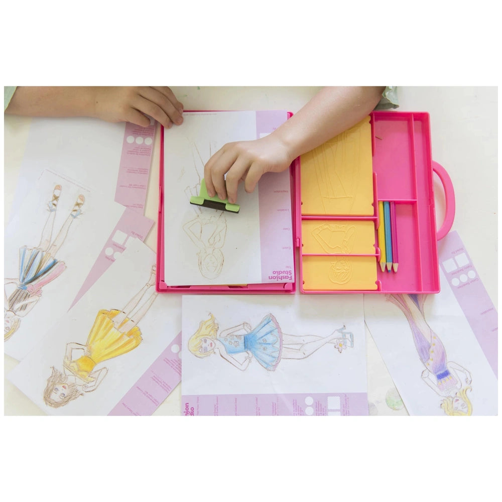 4M KidzMaker My Design Portfolio Fashion Studio with colorful crayons, a yellow pencil, and a pink container on a white table