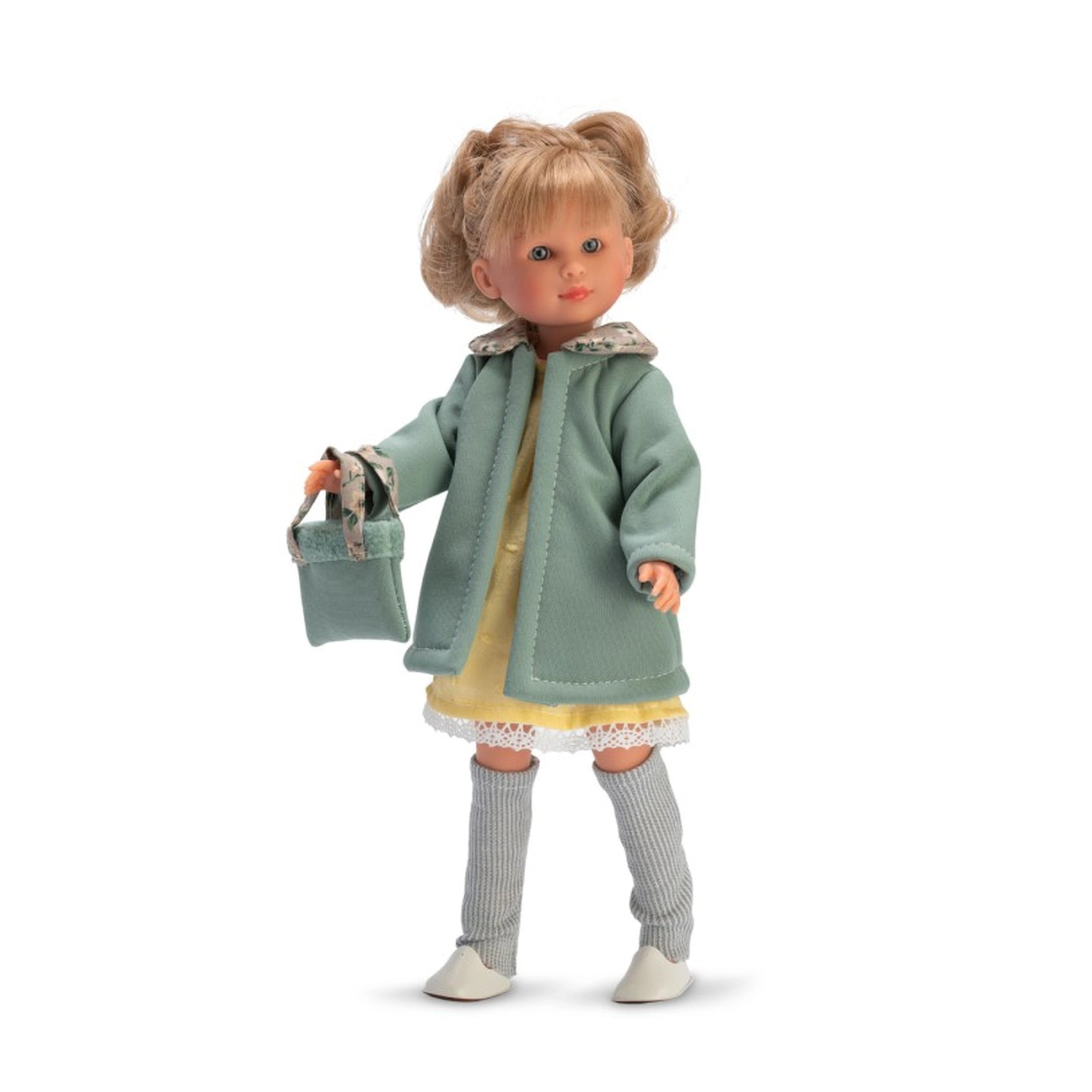 Celia doll in a green coat with stylish blonde hair, yellow dress, gray leggings, white shoes, and a matching handbag.