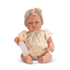 Oli Romper Spring Collection Doll, 30 cm, in floral romper, holding a toy bottle with a beige headband on a white background.