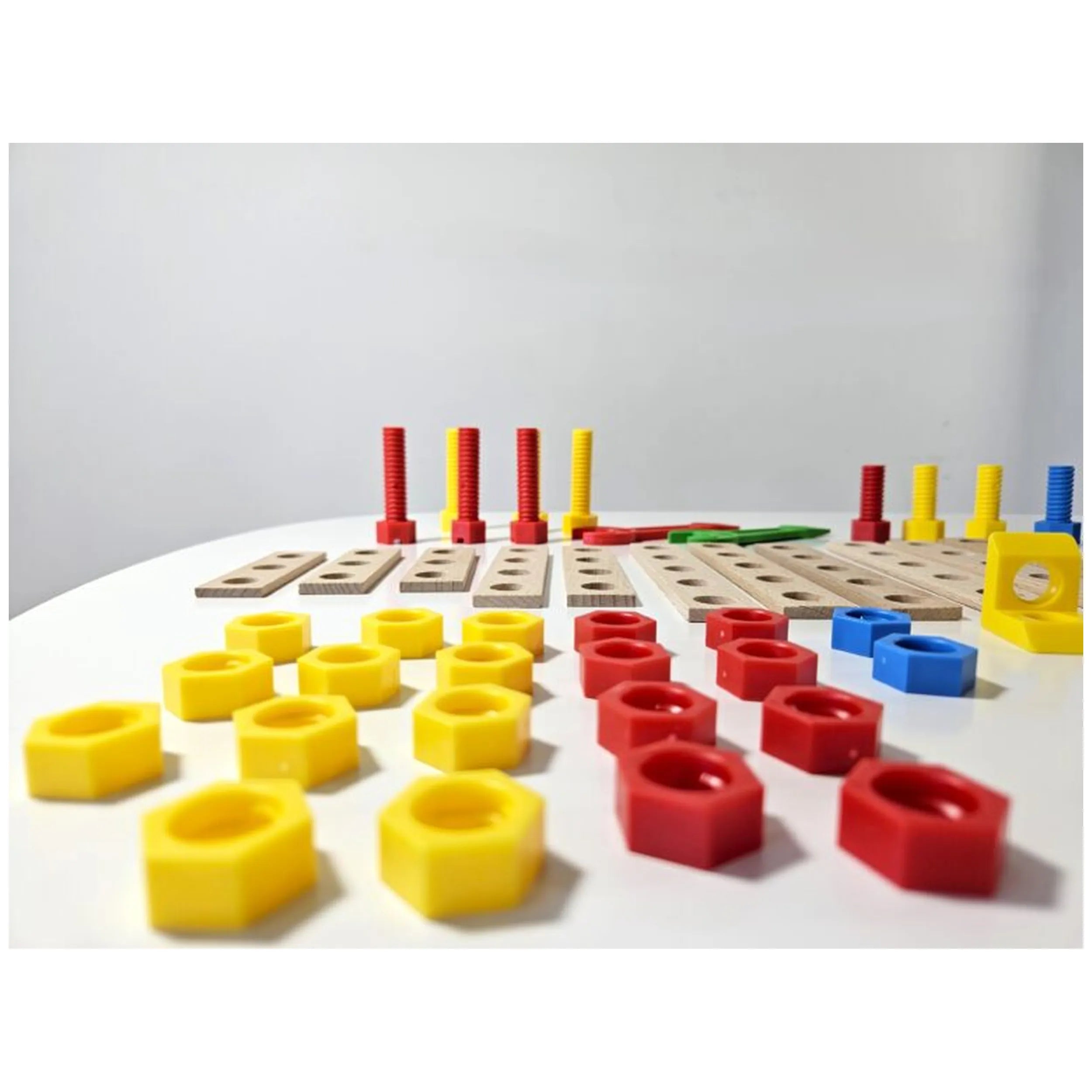 Colorful wooden and plastic pieces from the Alexander Constructor Junior Airplane Set scattered on a white surface.