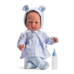 Lifelike baby doll in blue polka dot outfit and bonnet, sitting with bottle beside.