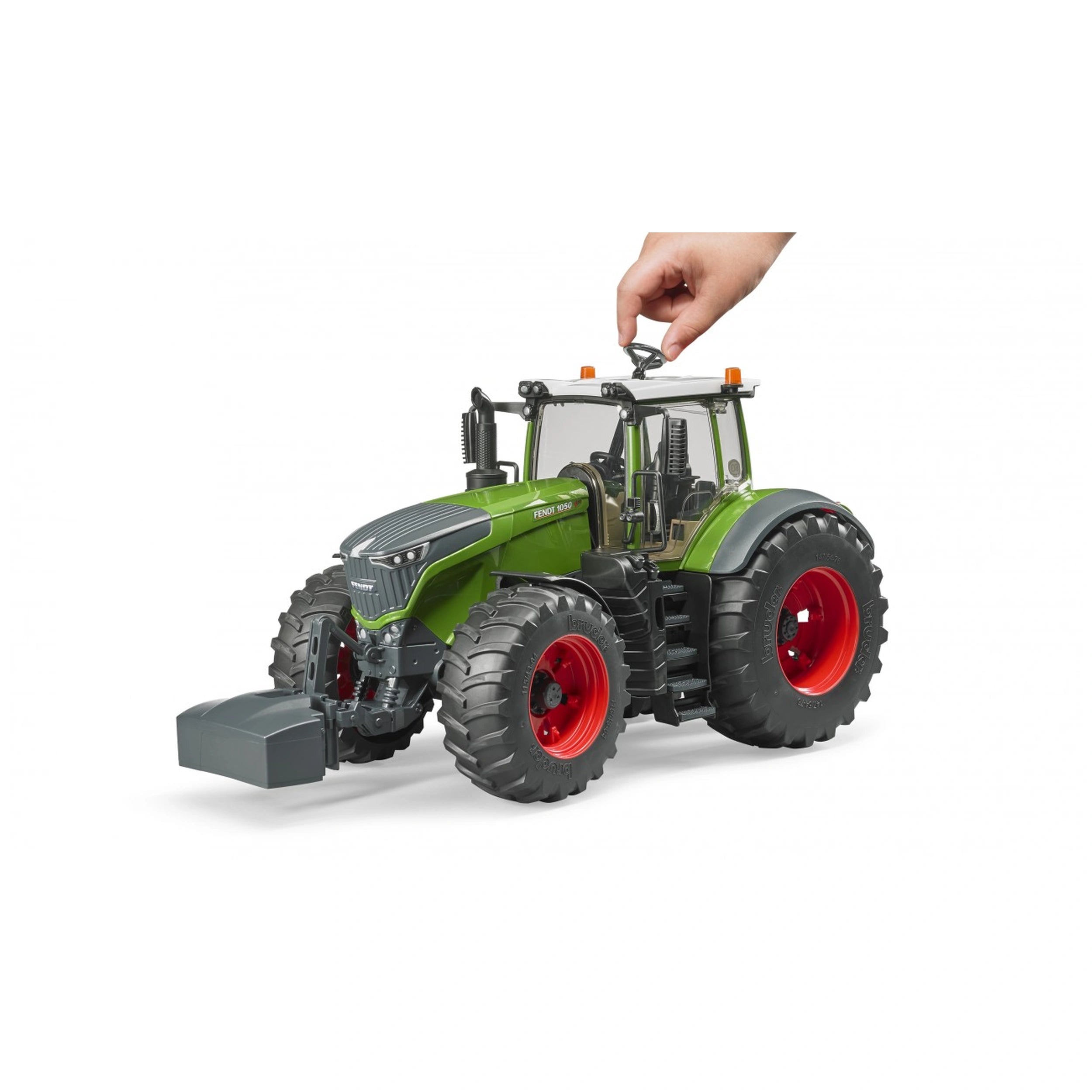 Hand adjusting the green Bruder Fendt 1050 Vario toy tractor, showcasing detailed design with red wheels.
