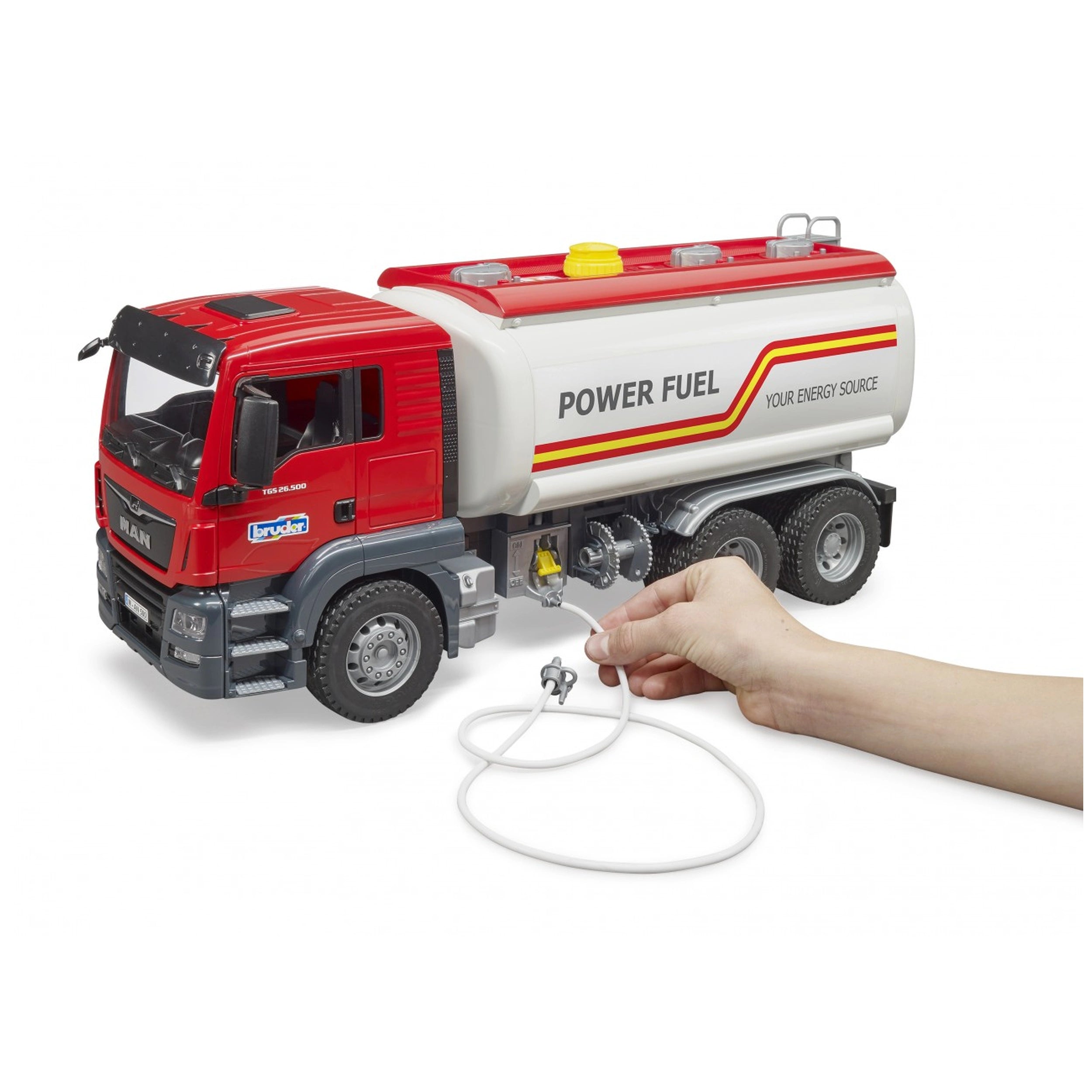 Red and white Bruder MAN TGS tank truck toy, 1:16 scale, with a hand holding the functional water hose.