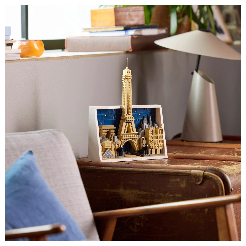 LEGO Architecture Paris set features a detailed Eiffel Tower model displayed on a wooden desk with a lamp.