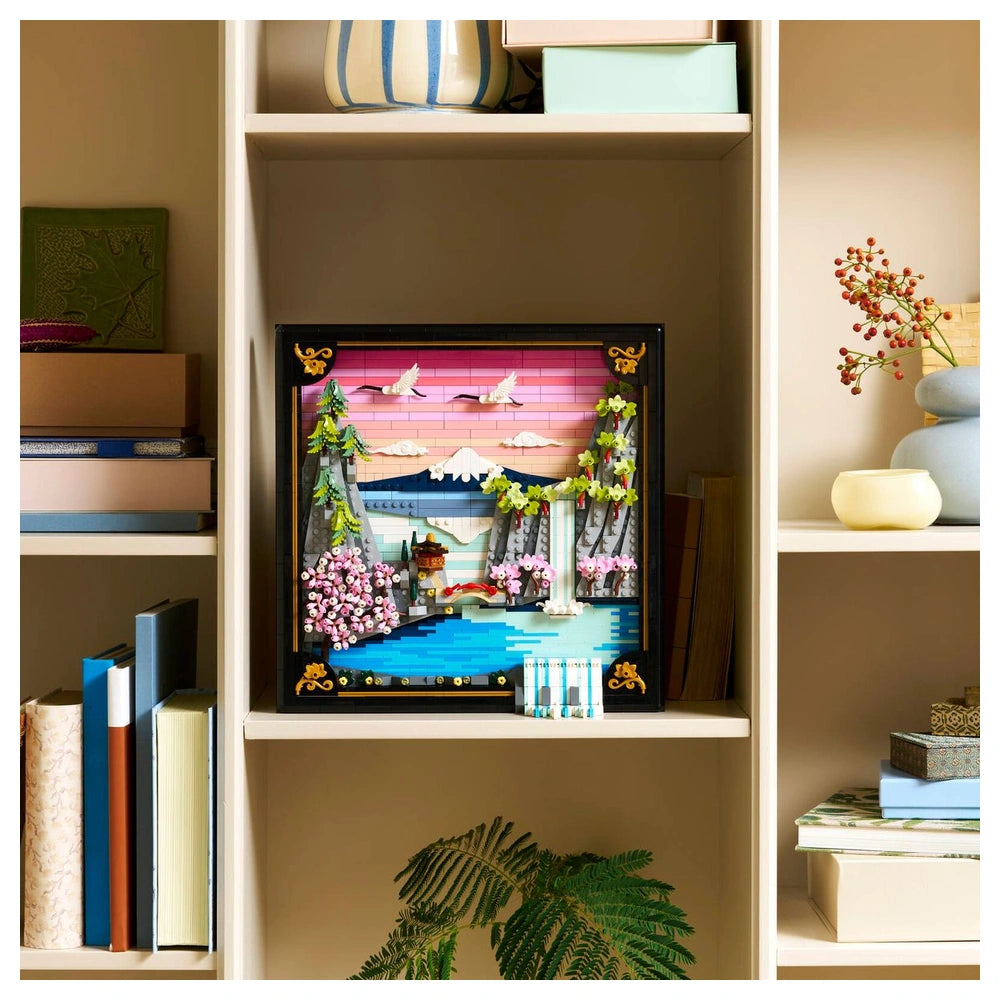 LEGO Art Japanese Cherry Blossom Landscape set displayed on a bookshelf surrounded by colorful books and a small plant.