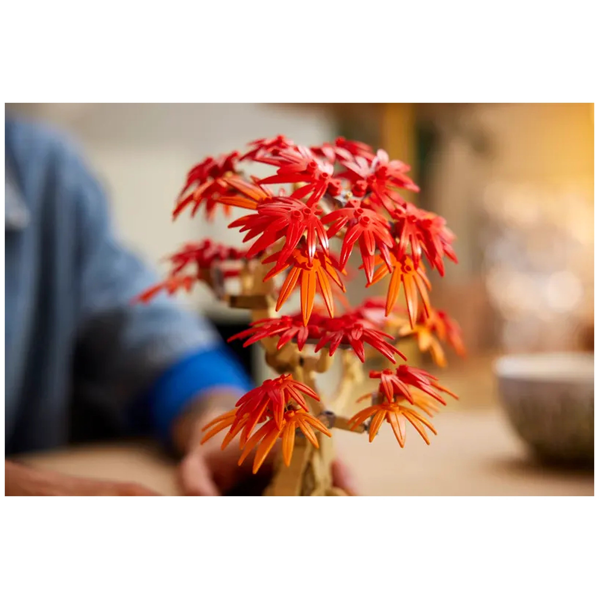 Vibrant LEGO® Japanese Red Maple Bonsai Tree with detailed red and orange leaves, set in a dark green pot, resting on a wooden table.