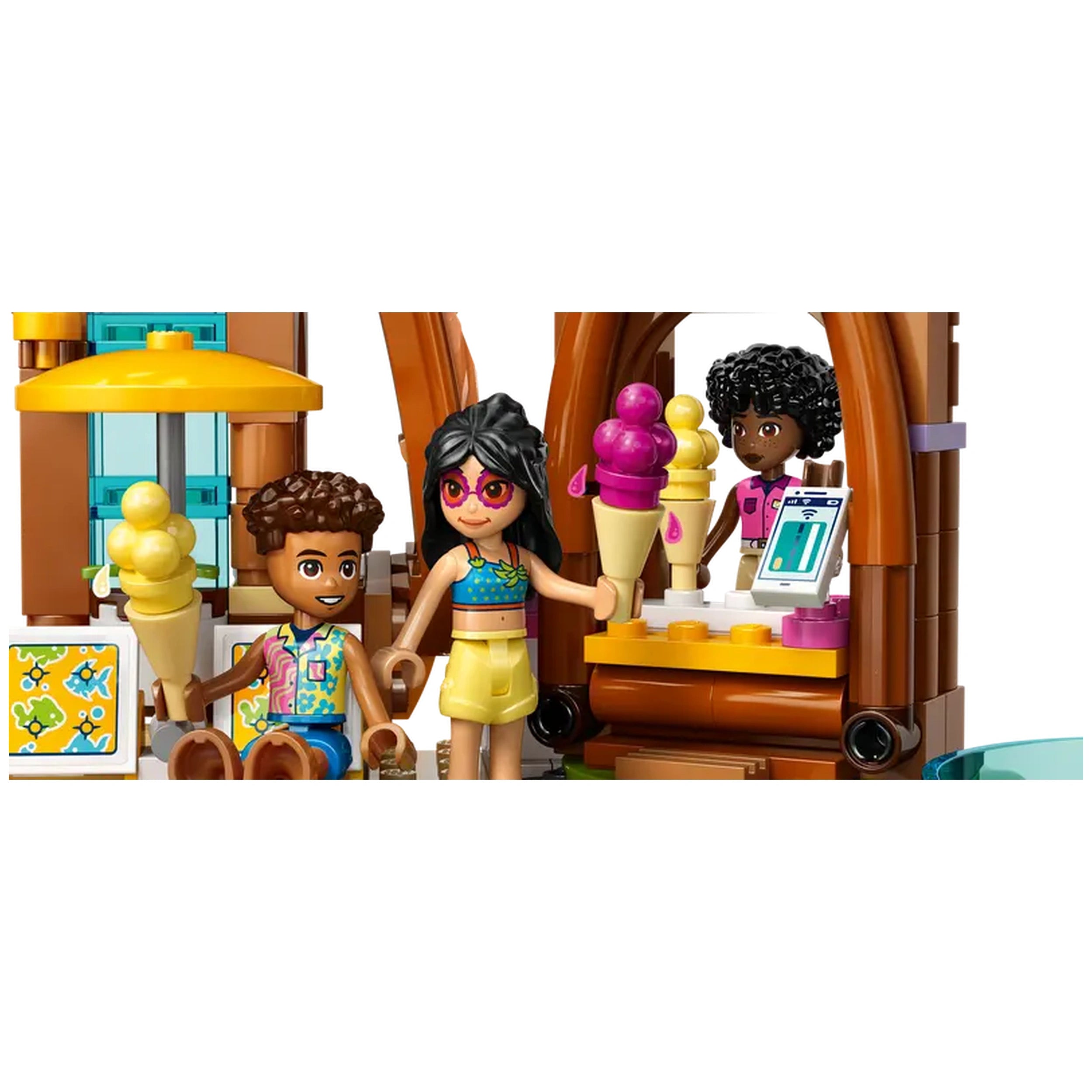 Two LEGO Friends minidolls holding ice cream cones stand in front of a colorful beach resort kiosk, with another minidoll behind the counter.