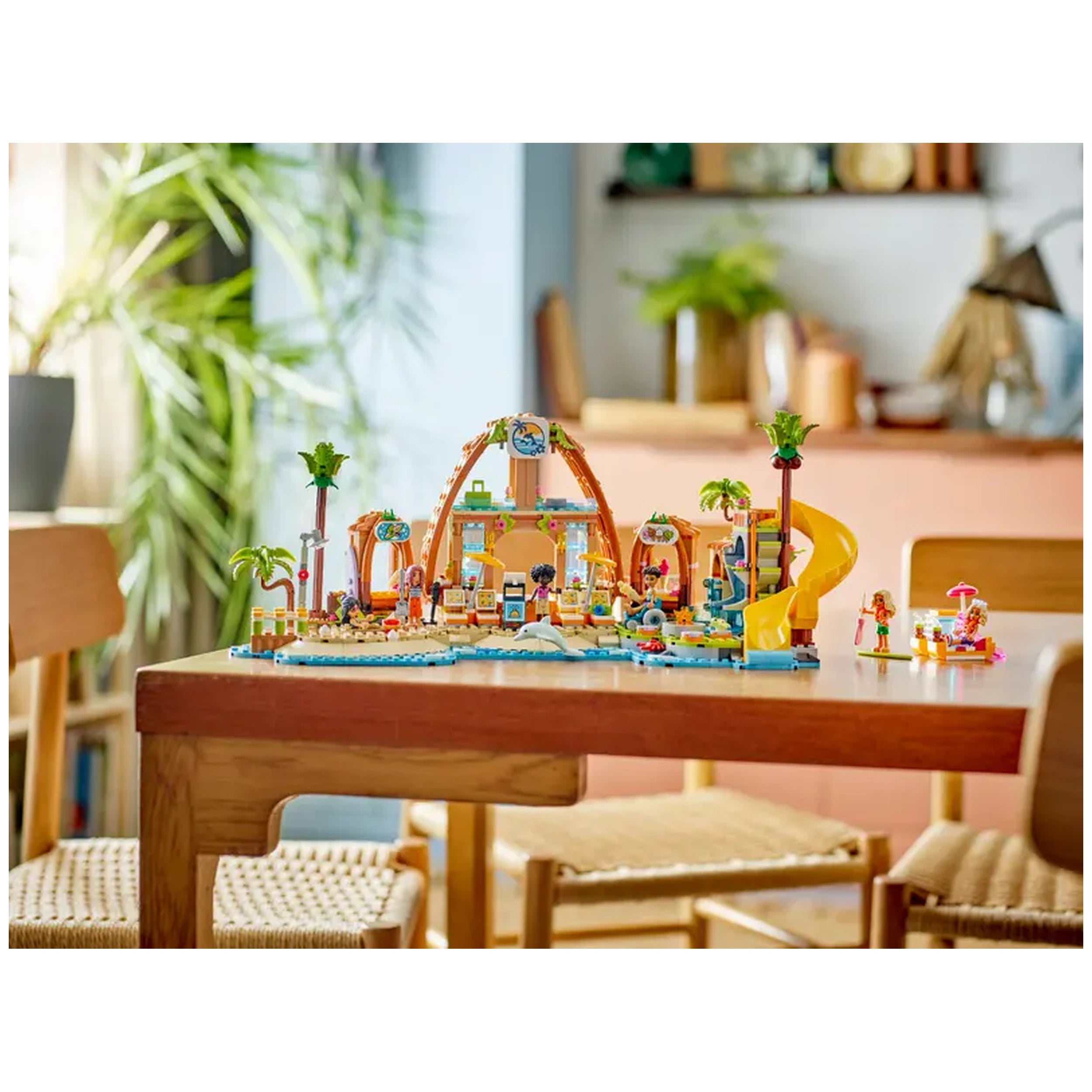 Colorful LEGO Family Vacation Beach Resort set on a wooden table, featuring six minidolls, a slide, palm trees, and beach accessories.