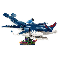 A blue LEGO® tulkun figure with a red tail and white markings, carrying a minifigure, hovers over a colorful seabed scene.