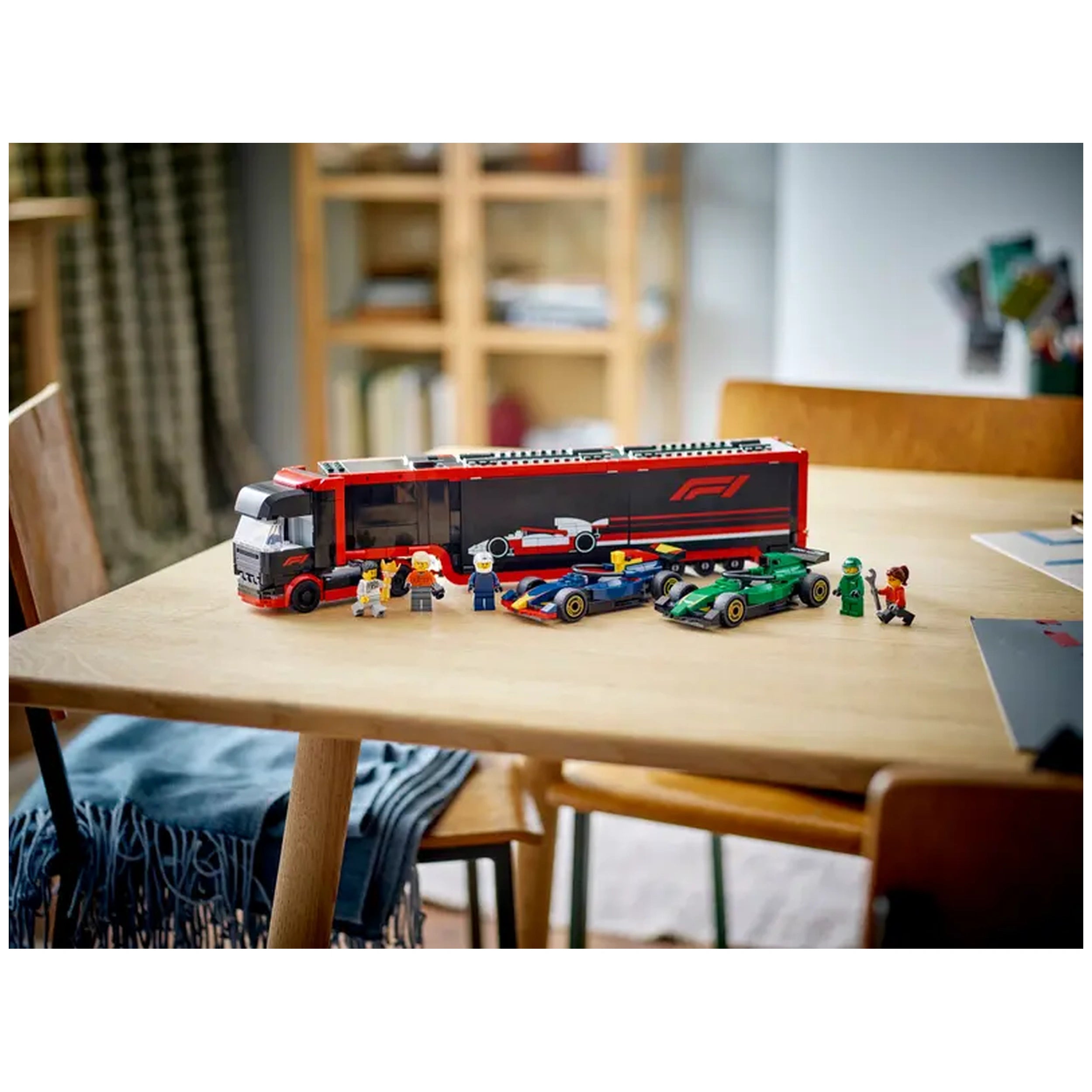 Bright red LEGO® F1® transport truck on a wooden table, surrounded by two F1® cars in blue and green, and four mini figures dressed in racing outfits, showcasing an immersive play environment.