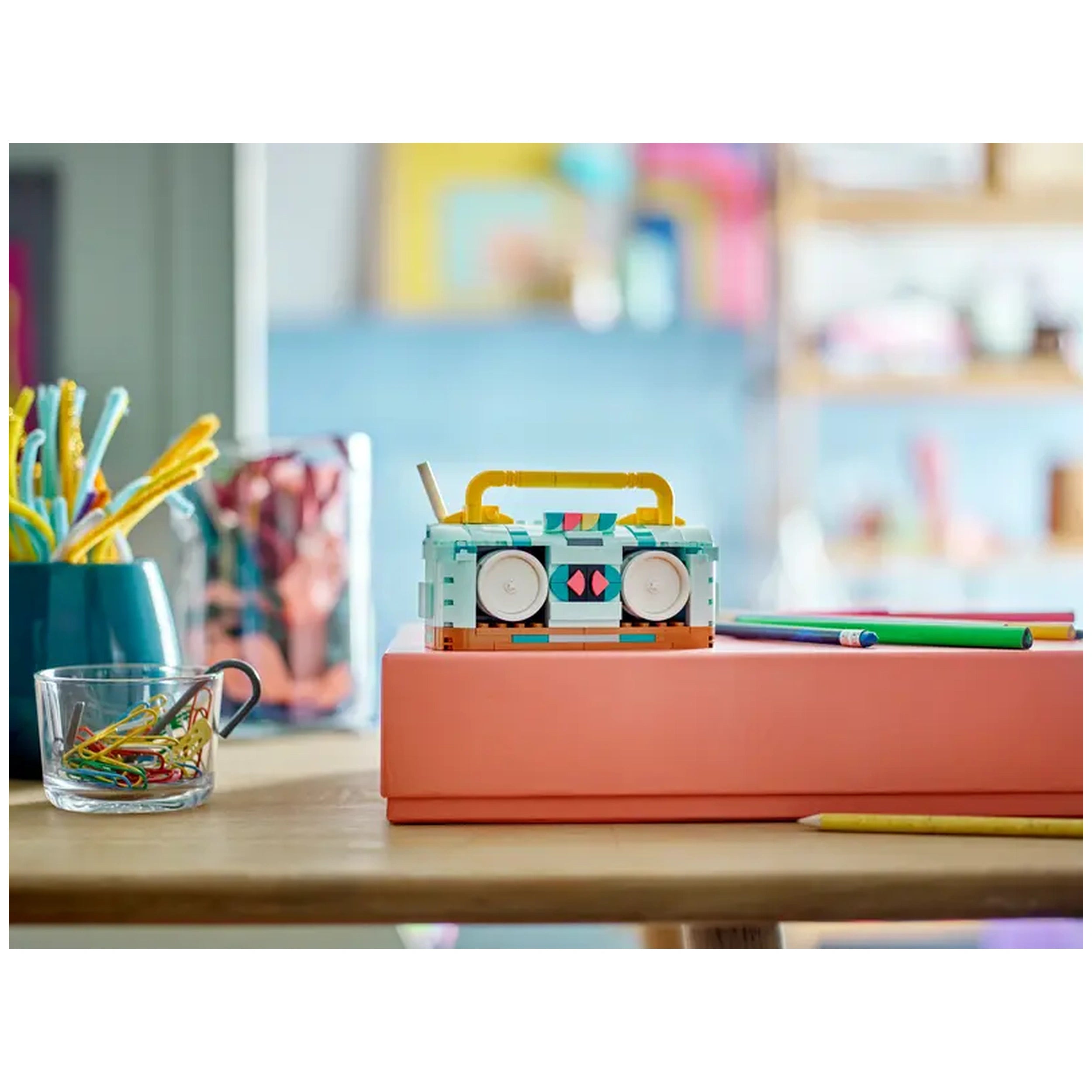 Colorful LEGO Creator Retro Roller Skate construction set displayed on a pink block, surrounded by art supplies and paper clips.