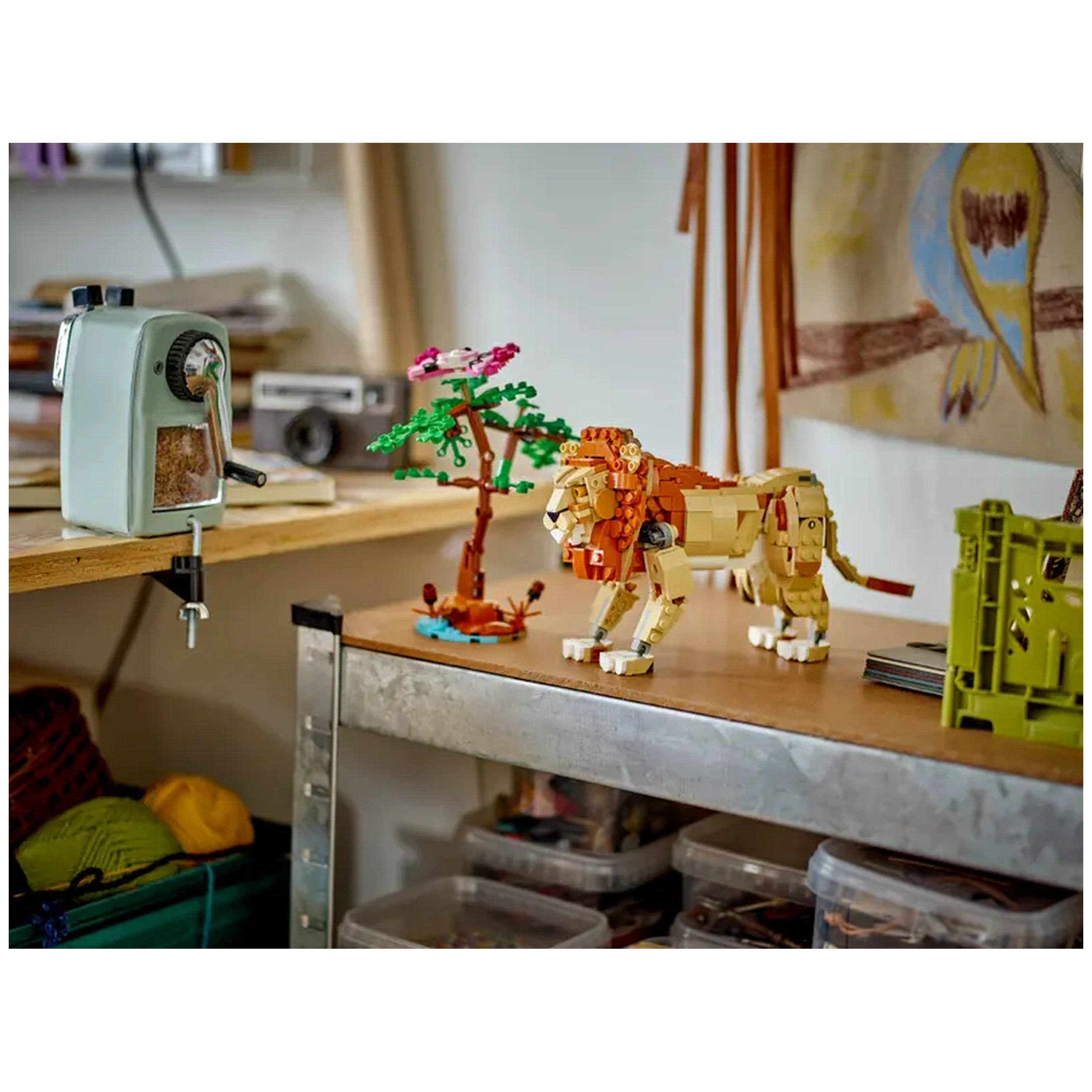 A vibrant LEGO Creator Wild Safari Animals set on a wooden table, featuring a posable lion, a colorful tree, and a vintage sharpener in the background.