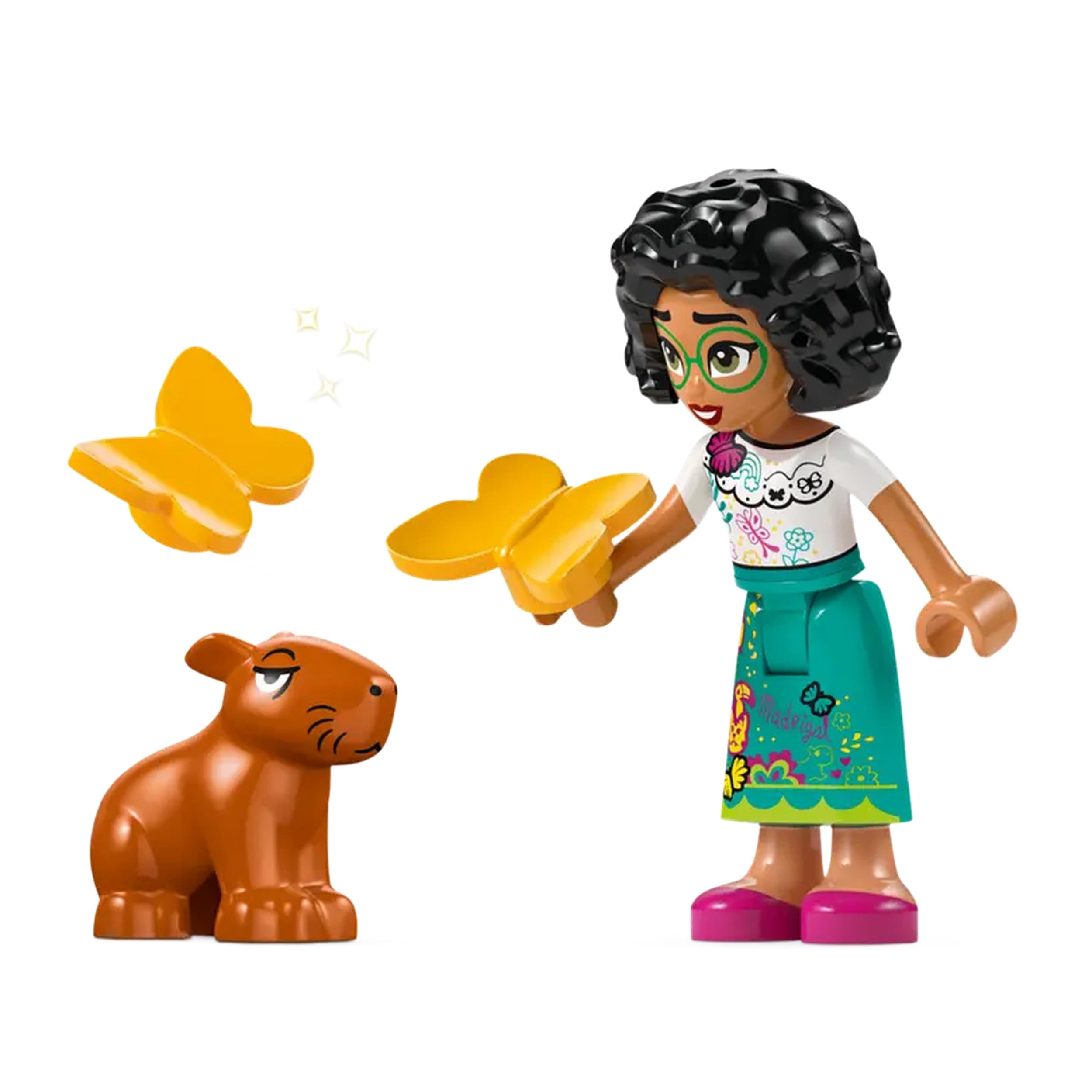 A mini-doll figure of Mirabel from Disney Encanto holds yellow butterfly pieces, smiling at a small brown capybara figure beside her.