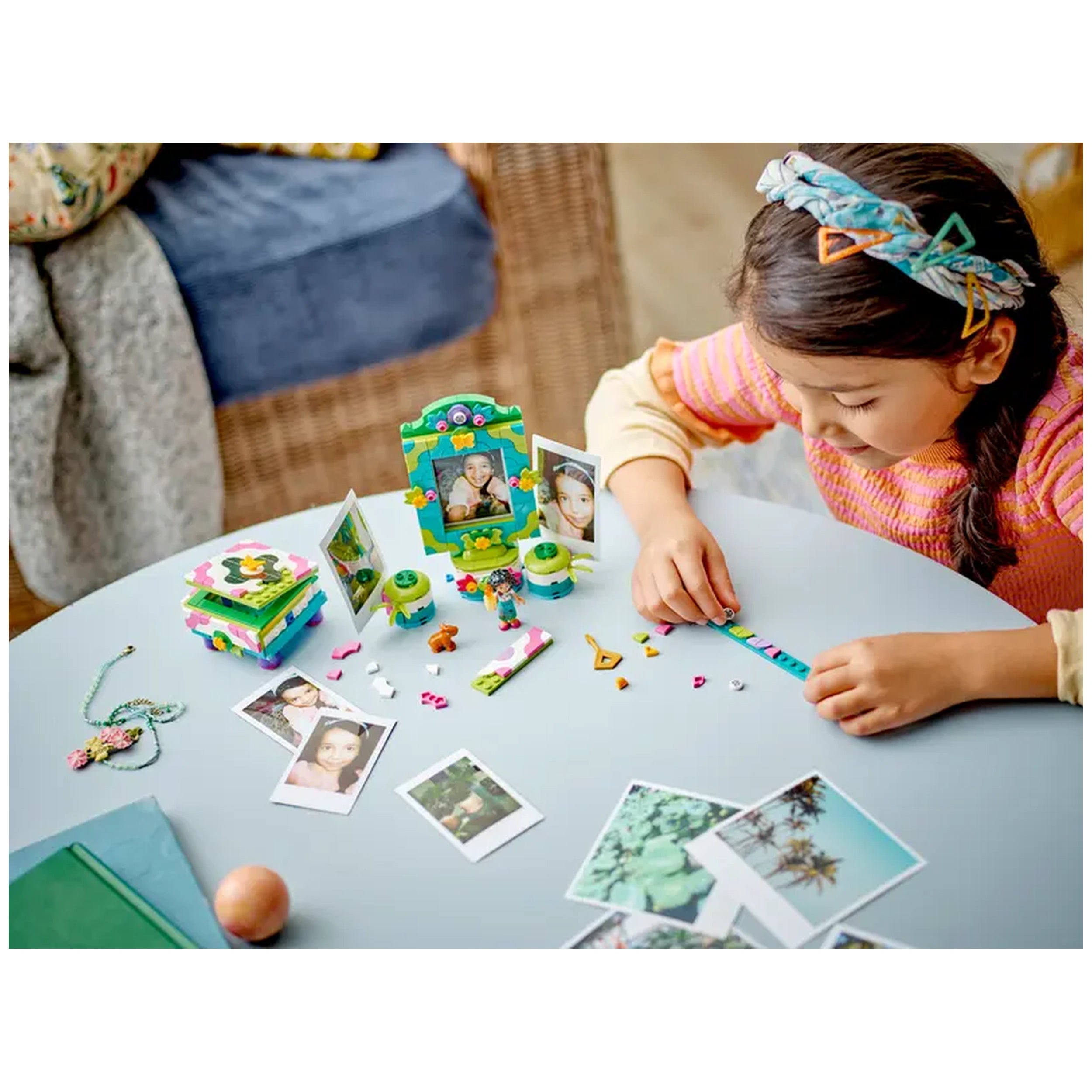 A child assembling the colorful LEGO® Disney Encanto Mirabel’s Photo Frame and Jewelry Box set, surrounded by small photo frames and a bracelet.