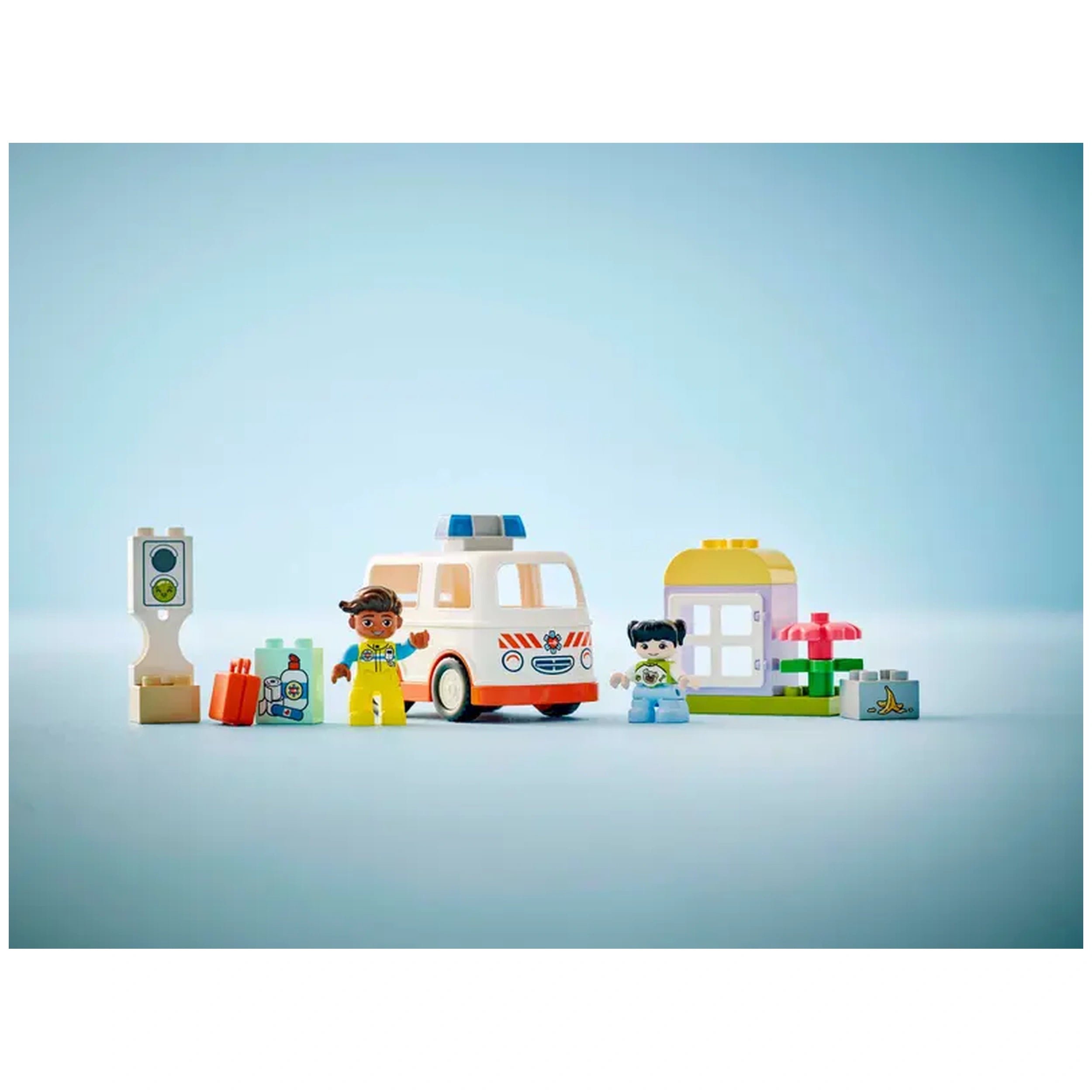 LEGO® DUPLO® Ambulance & Driver set featuring a smiling paramedic in yellow and a girl in blue, alongside an ambulance toy, traffic light, and fun building elements against a soft blue background.