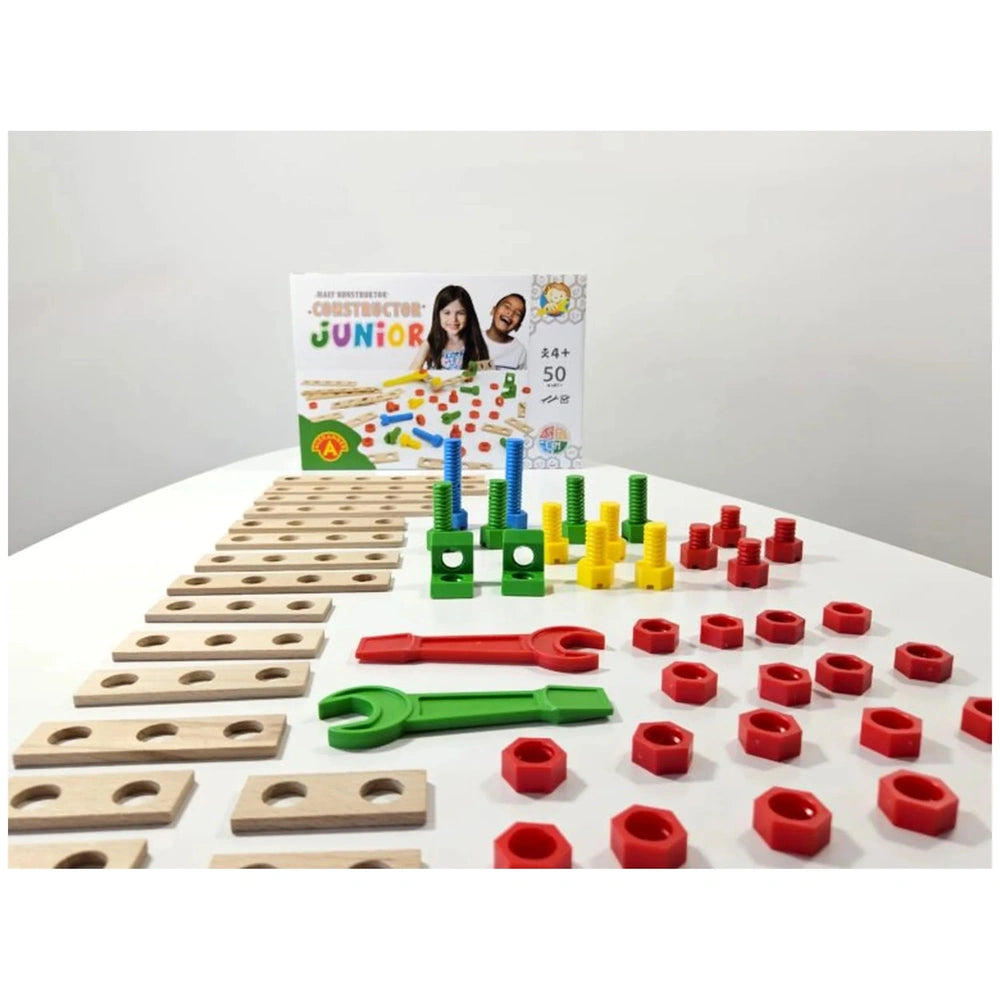 Colorful Alexander Constructor Junior set with wooden boards, red and yellow nuts, green and blue connectors, and wrenches on a white surface.