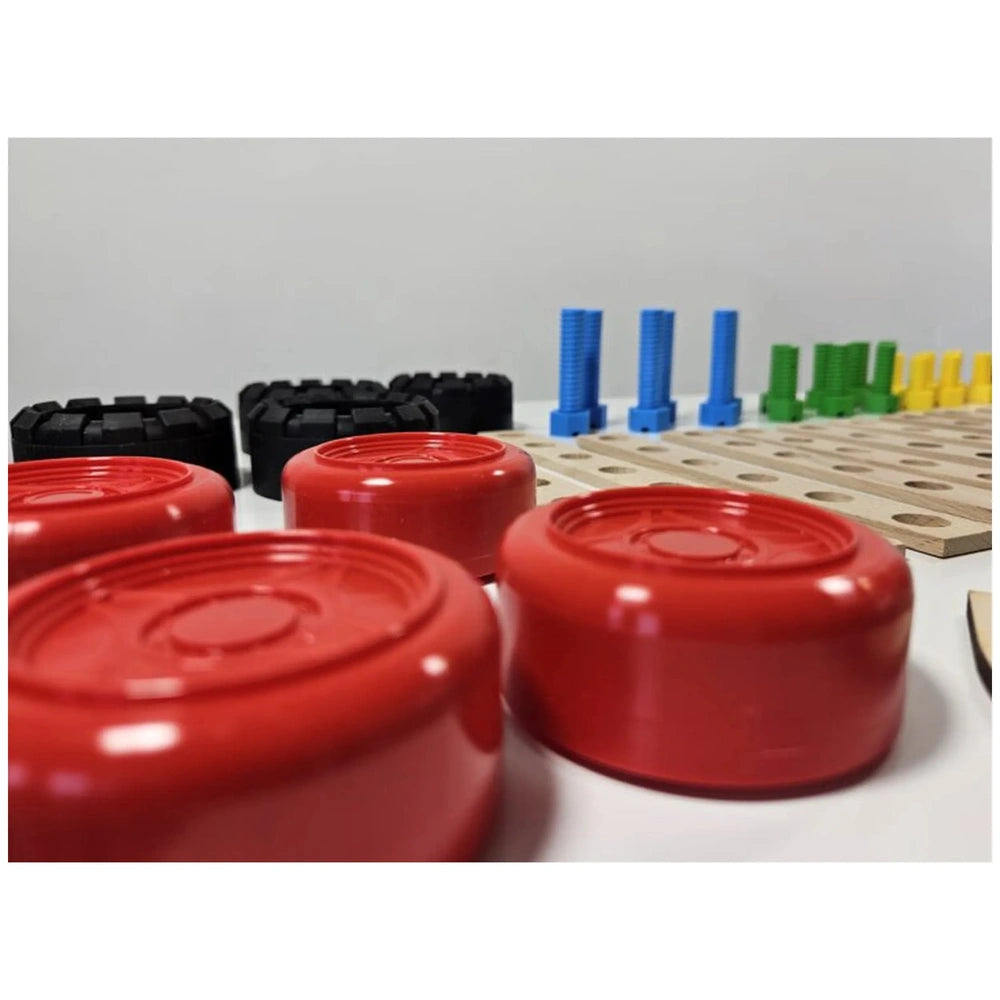 Colorful construction pieces, including red wheels, black tires, blue bolts, on a table.