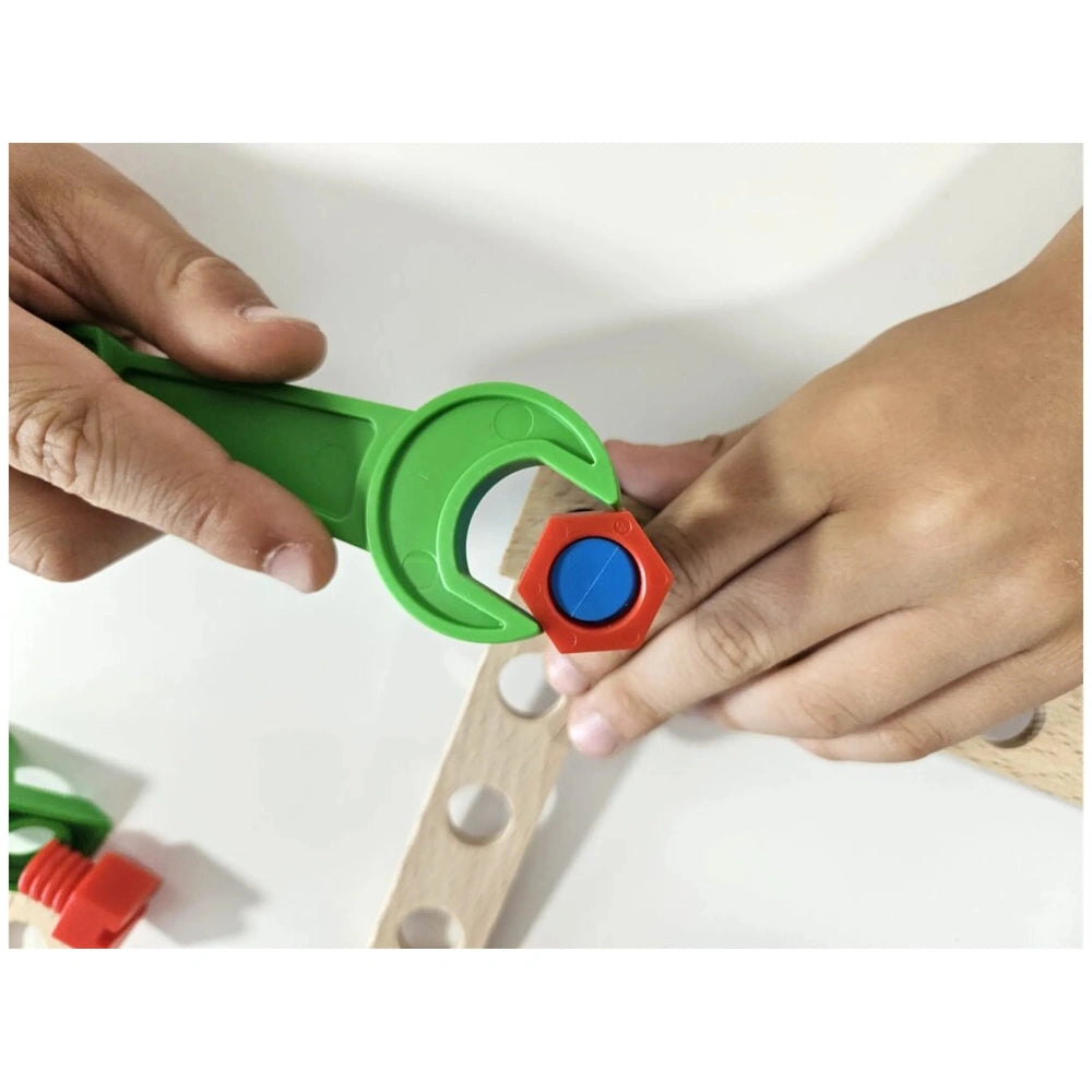 Child assembling wooden helicopter using green plastic wrench and colorful screw on pre-drilled plank.