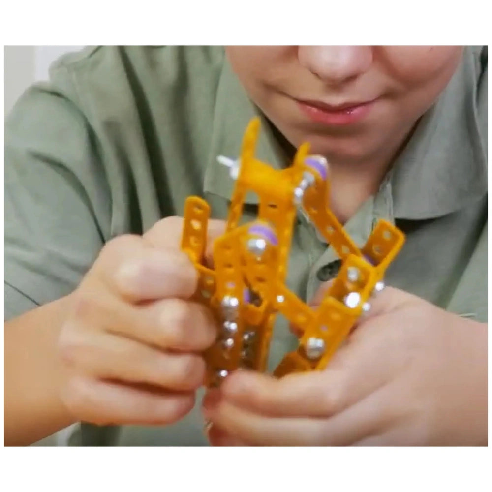 Child assembling orange and purple metal construction set, focusing intently on connecting pieces from Alexander Constructor Pro.