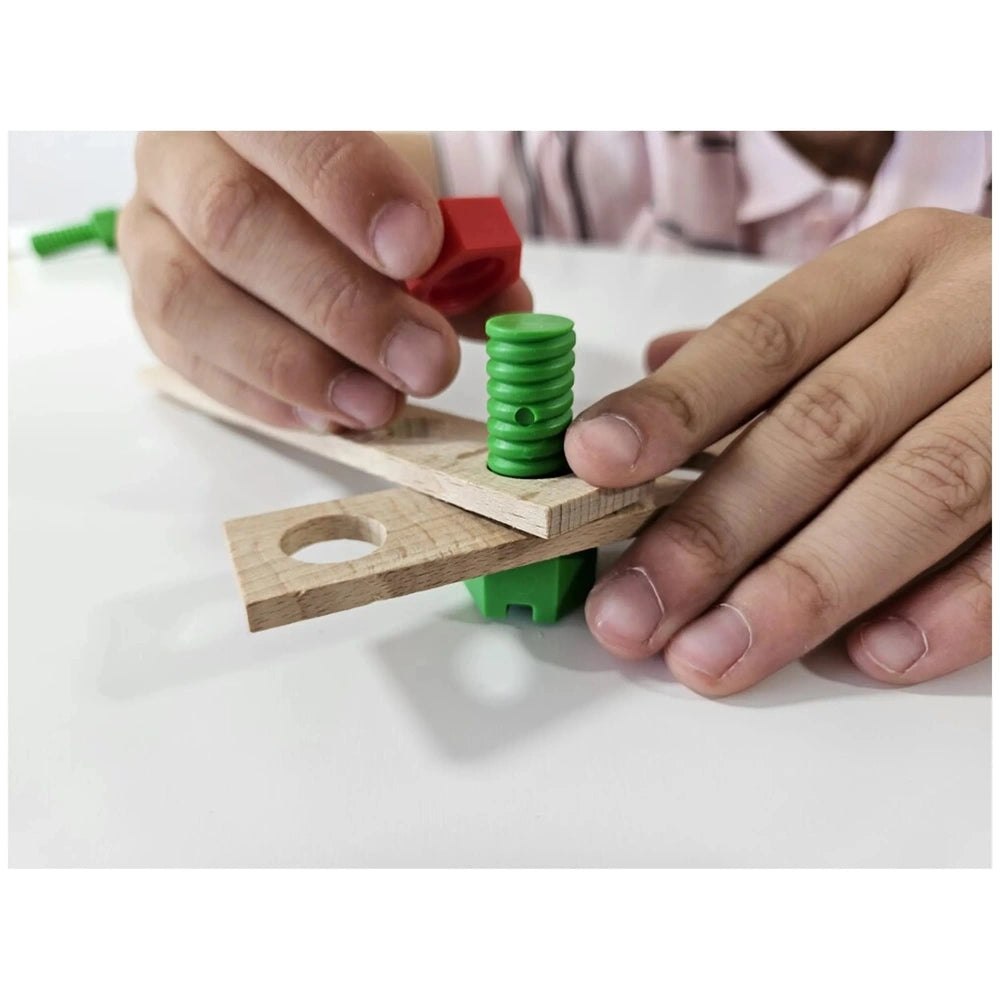 Child assembling Alexander Maly Constructor race car using wooden board, green screw, and red connector.